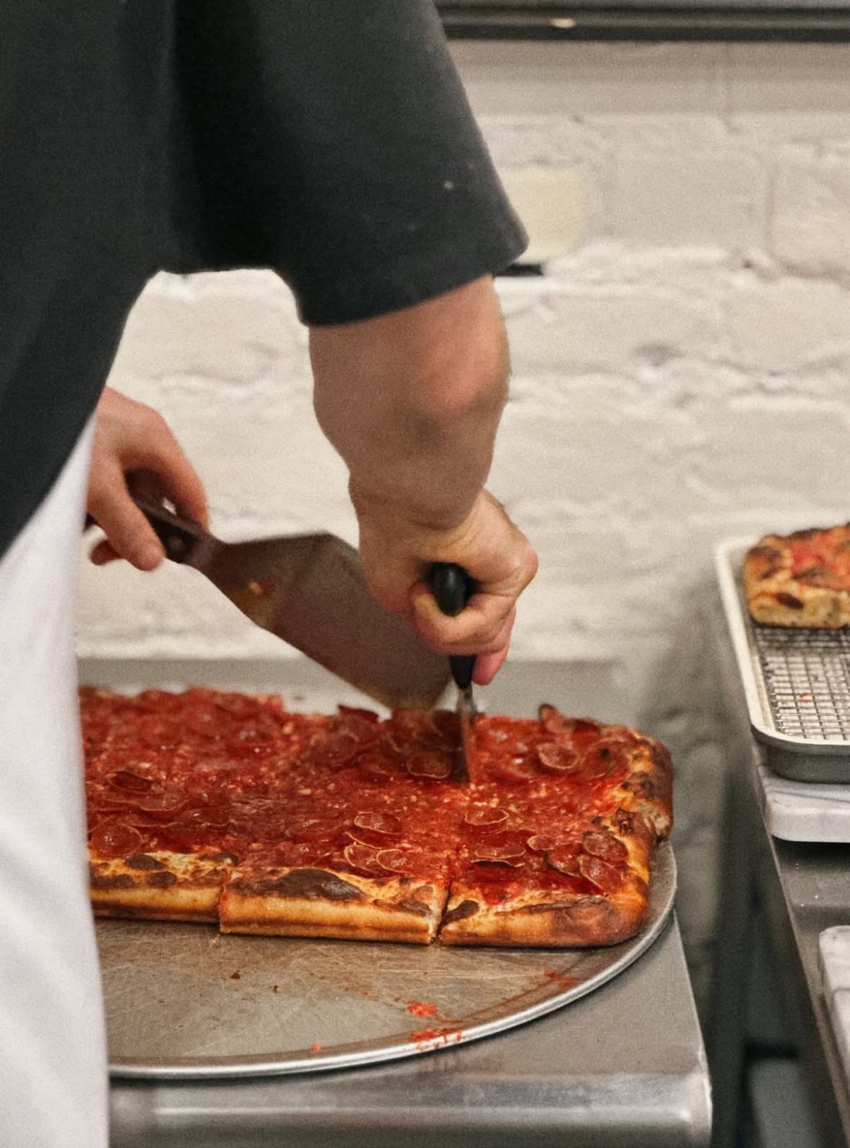 Cutting a square pepperoni pie straight off the pan