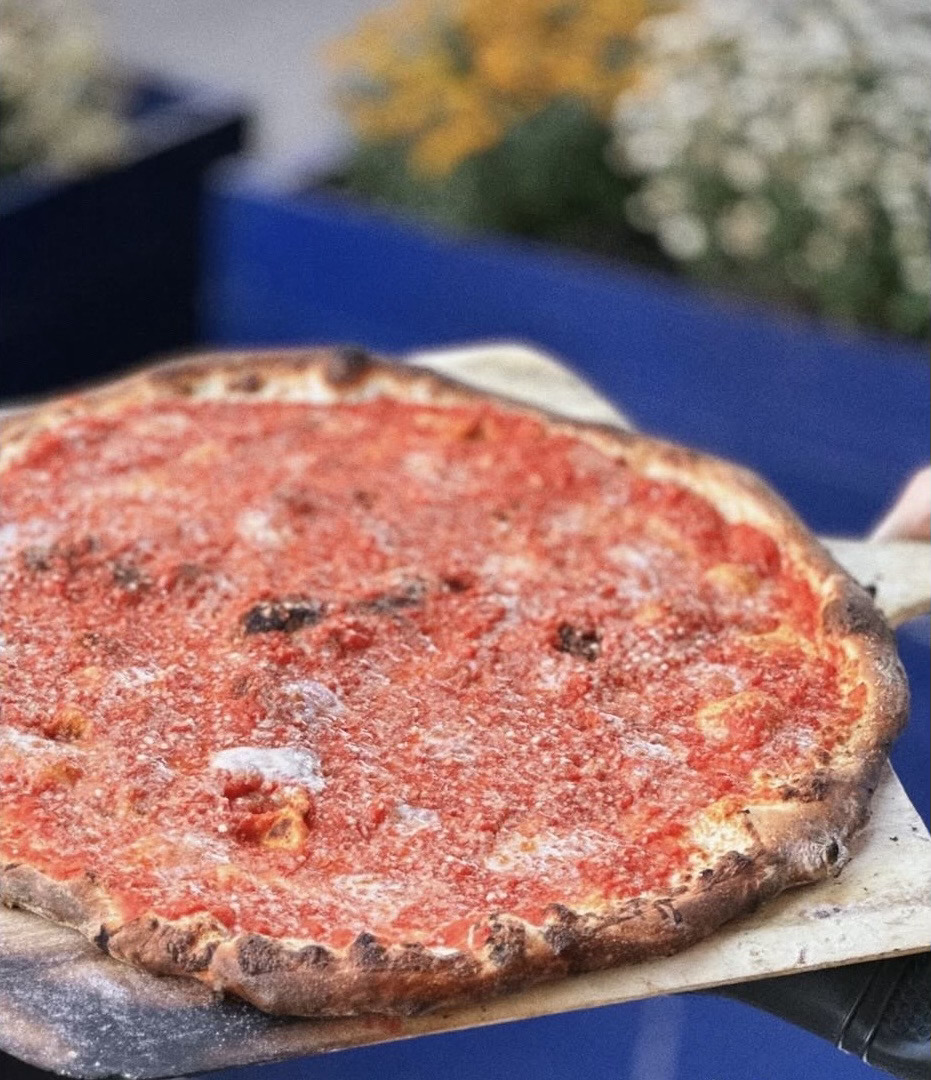 A round, thin-crust tomato pie straight off the peel
